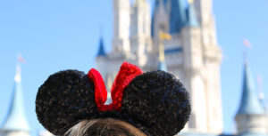 Disney blogger Sparkly Nicole wears sequin Minnie ears looking at Cinderella Castle. The photo is taken from behind, just showing the top of the ears and the castle off in the distance at Magic Kingdom at Walt Disney World Resort.