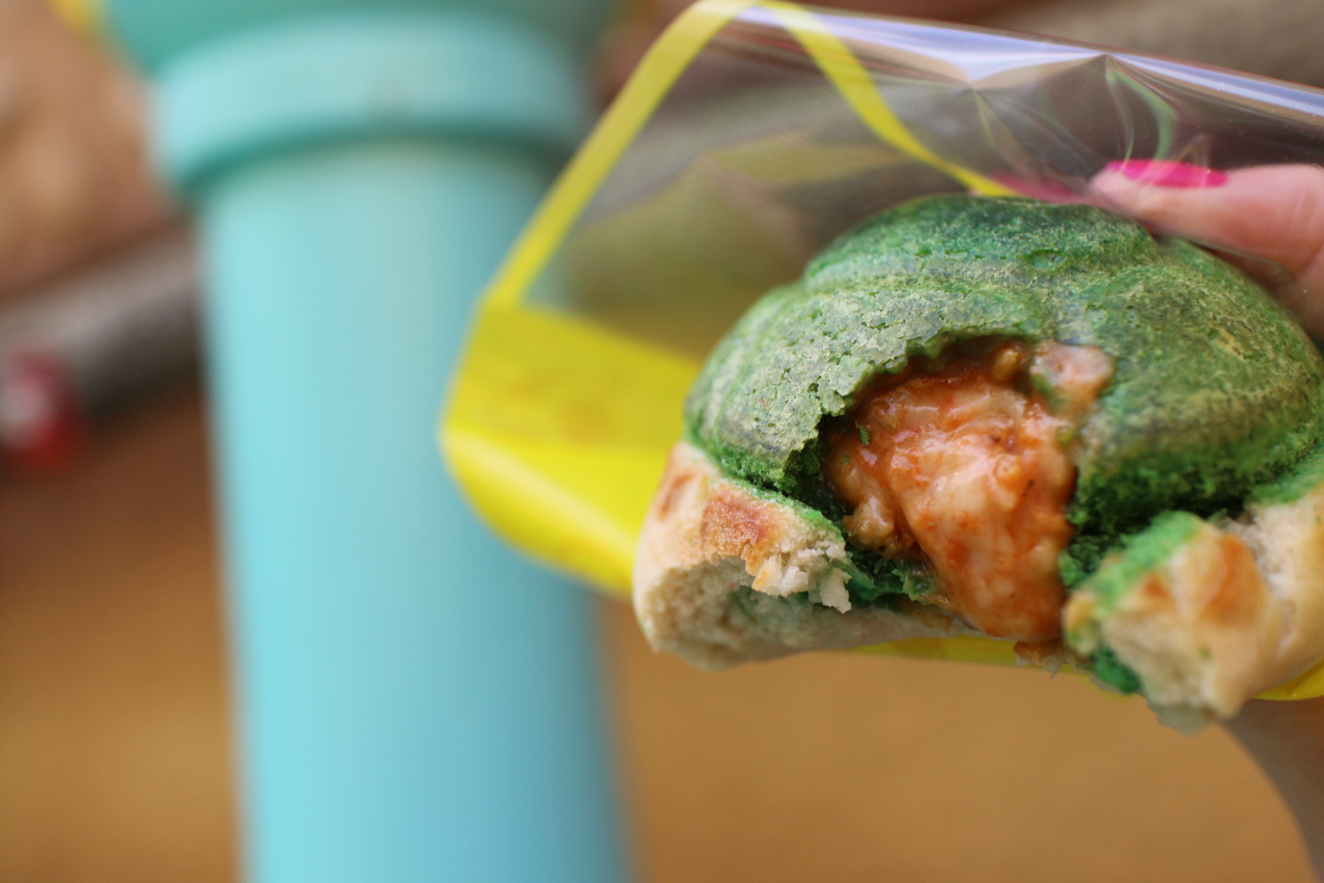 A green turtle shell snack at Epic Universe in Super Nintendo World. The small, round calzone is filled with cheese.