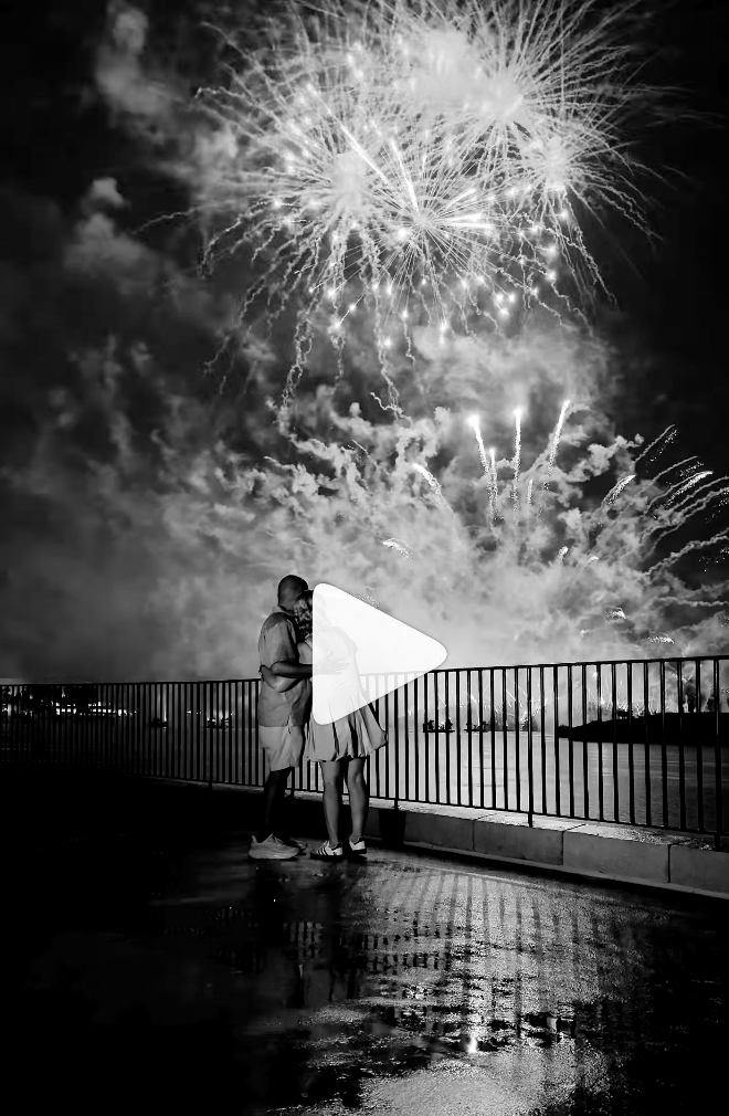 A couple poses in front of the fireworks at Epcot after their Disney Wedding. The content is in black and white.